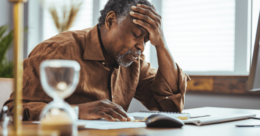 Stressed Black man hunched over a notebook with his hand on his head