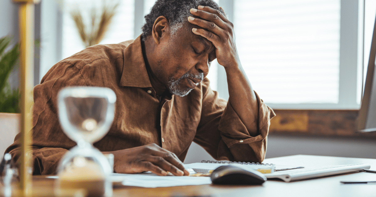 Stressed Black man hunched over a notebook with his hand on his head
