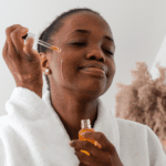 Black woman with prurigo nodularis applying tea tree oil to her face