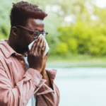 Man with glasses blowing his nose
