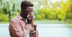 Man with glasses blowing his nose