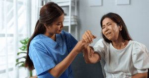 Nurse helping Asian woman with myasthenia gravis (MG) with arm weakness