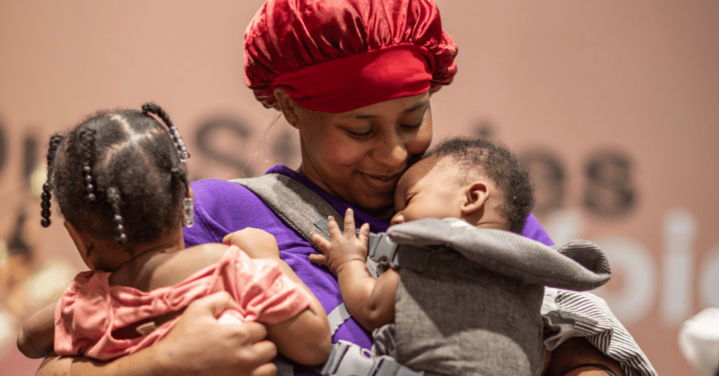 Black mom holding her baby girl and boy on each arm