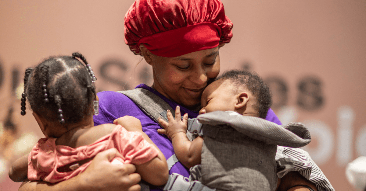 Black mom holding her baby girl and boy on each arm