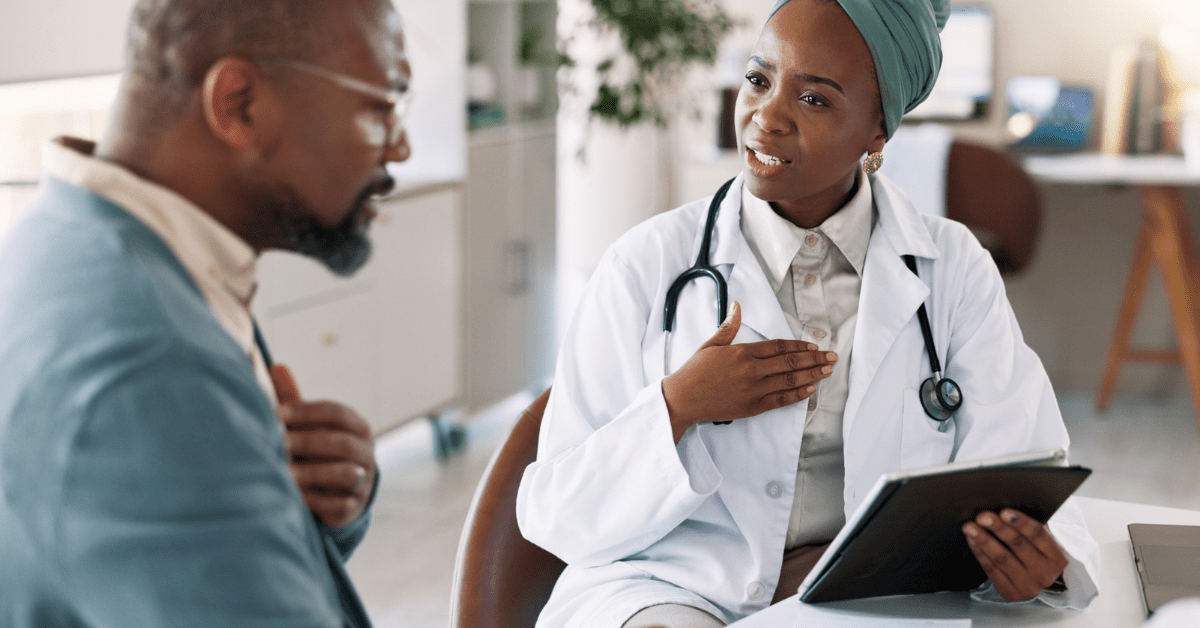 Black female doctor explaining asthma symptoms to Black man holding his chest