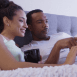 Man and woman sitting in bed, looking for information on their tablet device together