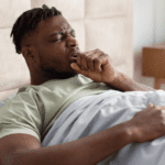 Black man coughing in bed