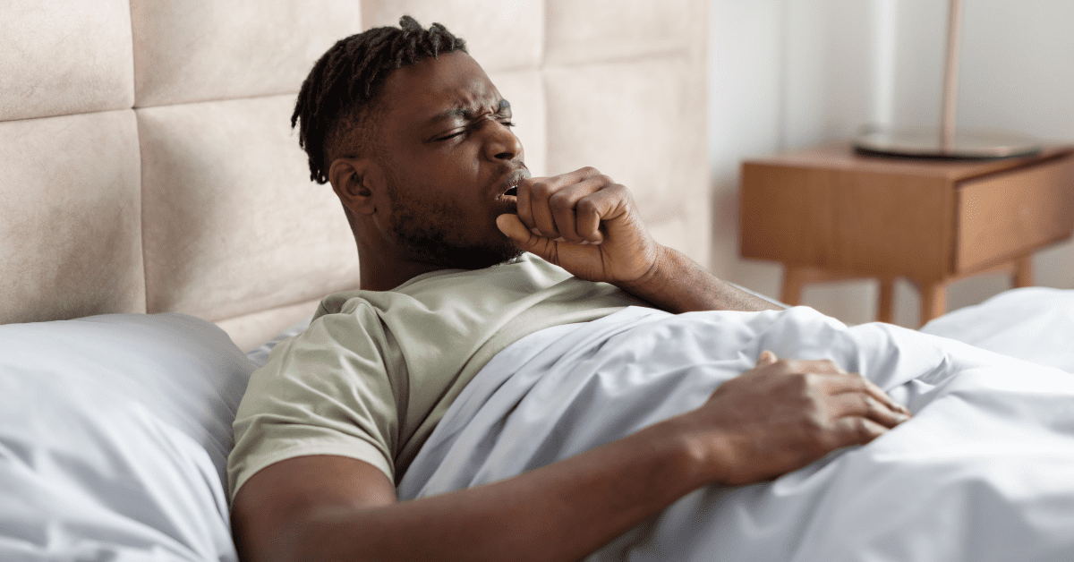 Black man coughing in bed