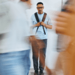 Man standing alone with a backpack as people pass by him in a blur