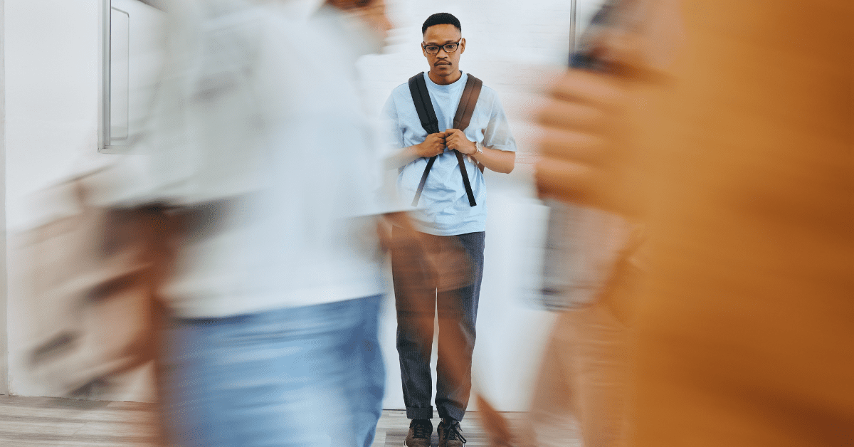 Man standing alone with a backpack as people pass by him in a blur