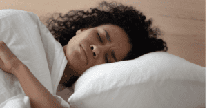 Close-up of woman laying on a pillow with a distressed expression and her eyes closed