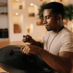 Black man meditating by using drumsticks on a metal drum circle