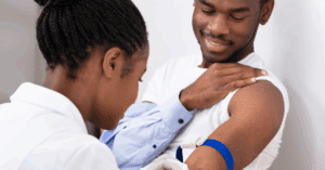 Close-up Of female doctor injecting Black male patient with syringe to collect a blood sample