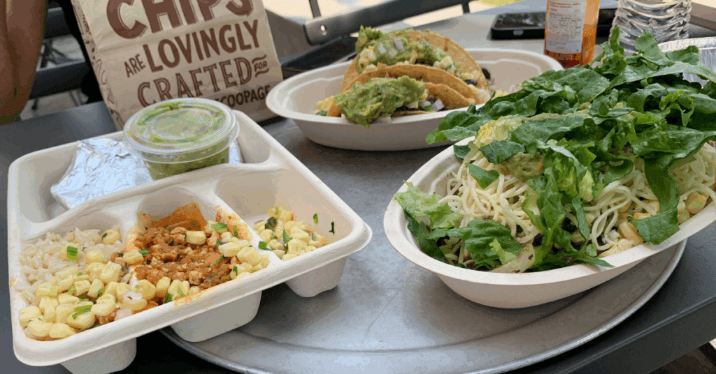 Burrito bowl, tacos, quesadilla, and a bag of chips from Chipotle sitting on a table