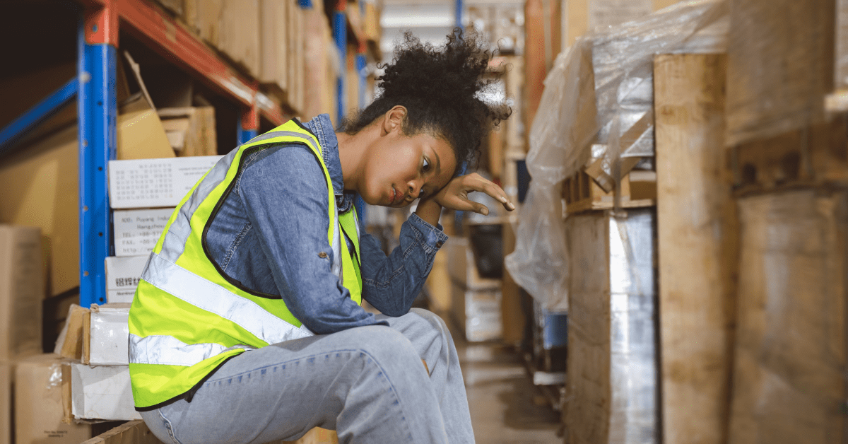 Tired, stressed woman worker working in warehouse cargo inventory industry.