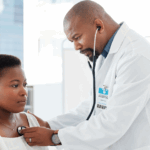 Doctor in a lab coat listening to patient’s heart using a stethoscope