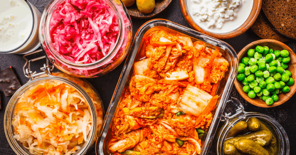 Overhead shot of fermented foods such as kimchi, pickles, sauerkraut, pickled onions, and yogurt