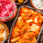 Overhead shot of fermented foods such as kimchi, pickles, sauerkraut, pickled onions, and yogurt