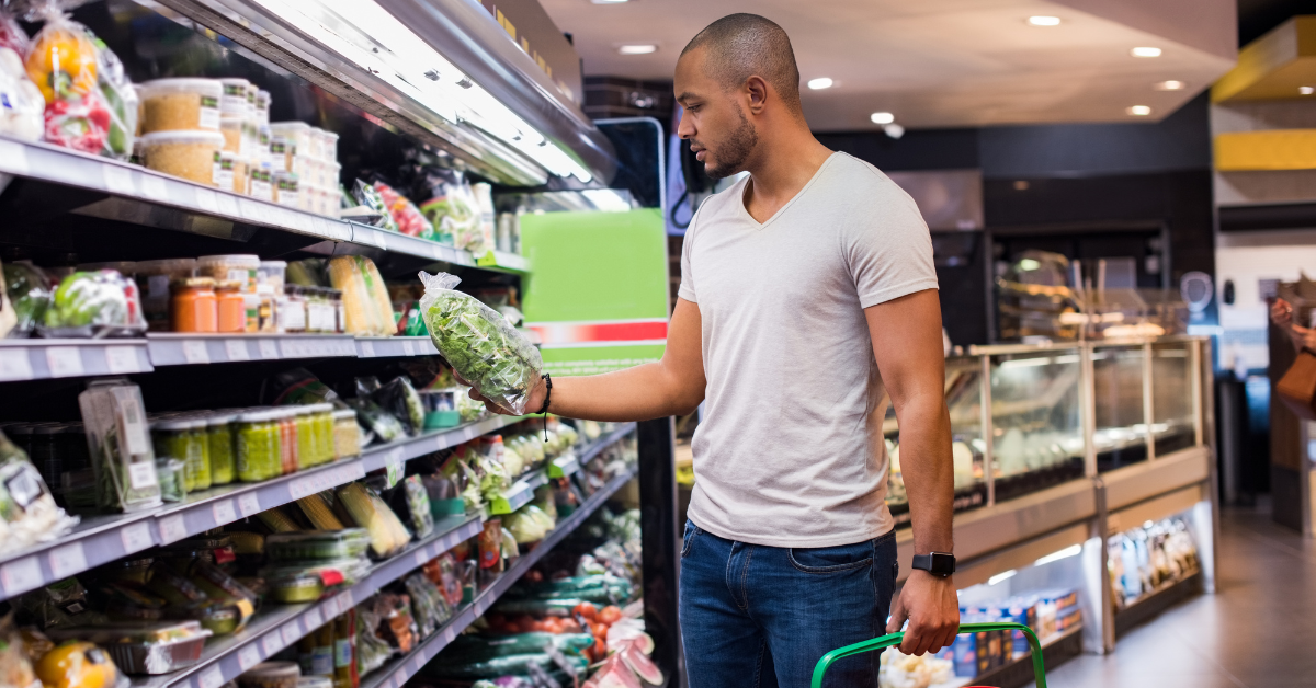 Young African American man at the grocery store, holding a bag of greens