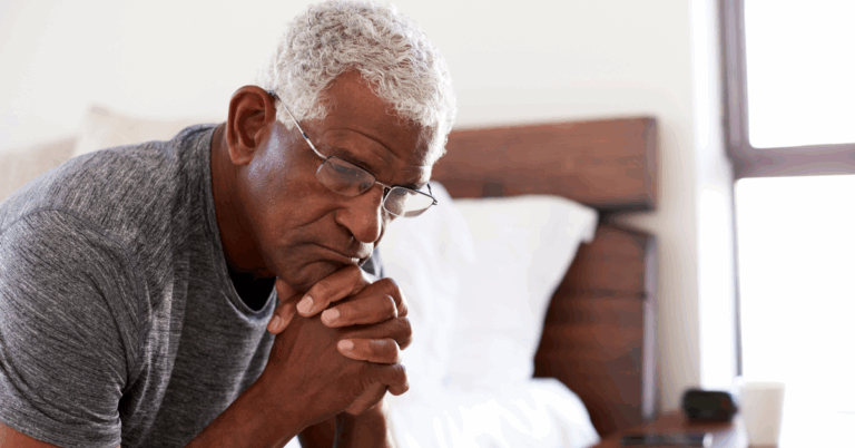 Soul Food Flavor Made IBD-Friendly 4 Close-up of a tired elderly Black man sitting on the edge of his bed, resting his chin on his hands