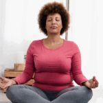 Middle-aged African American woman sitting with her legs crossed on a yoga mat in a meditative pose
