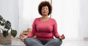 Middle-aged African American woman sitting with her legs crossed on a yoga mat in a meditative pose