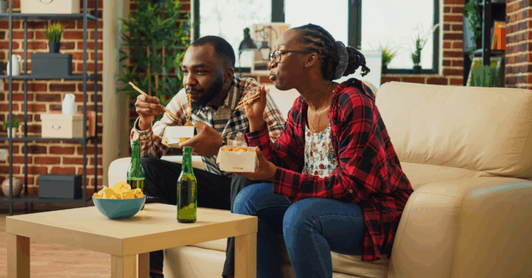 7 Latest Cancer Research Breakthroughs to Know About 1 Young Black couple on the couch eating Chinese takeout with chopsticks