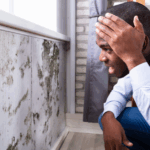 Young Black male looking at a moldy wall with a shocked expression
