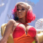 American rapper, Cardi B, in a rainbow wig, holding a white fan in her left hand