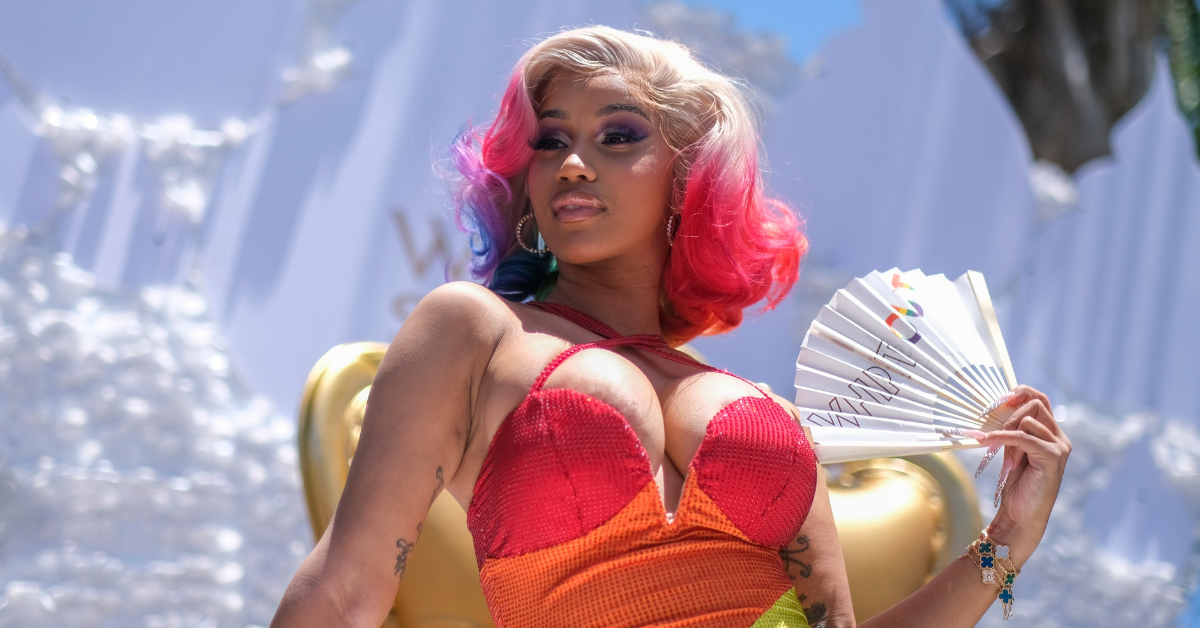 American rapper, Cardi B, in a rainbow wig, holding a white fan in her left hand