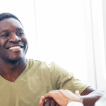 Young African American man smiling and shaking a doctor’s hand during prostate cancer screening.