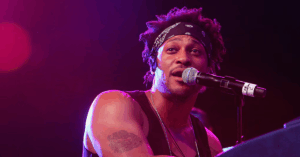 Neo-soul singer, D’Angelo, singing into a mic on stage before his passing from pancreatic cancer