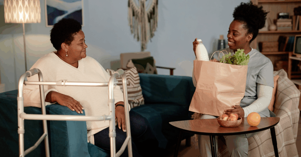 Full length shot of Black female caregiver delivering groceries to senior mom with Alzheimer’s