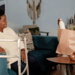 Full length shot of Black female caregiver delivering groceries to senior mom with Alzheimer’s