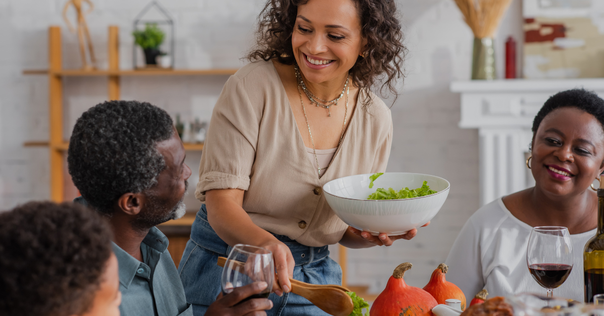 African American woman using tongs to serve salad to family and son during a Thanksgiving celebration
