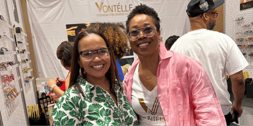 Tiffany Whitlow, co-founder and CDO, Acclinate, and Tracy Vontélle Green, Co-Founder and CEO of Vontélle Eyewear, wearing glasses standing in front of a white banner at Vontélle Eyewears’ vendor booth.
