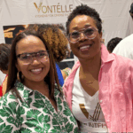 Tiffany Whitlow, co-founder and CDO, Acclinate, and Tracy Vontélle Green, Co-Founder and CEO of Vontélle Eyewear, wearing glasses standing in front of a white banner at Vontélle Eyewears’ vendor booth.