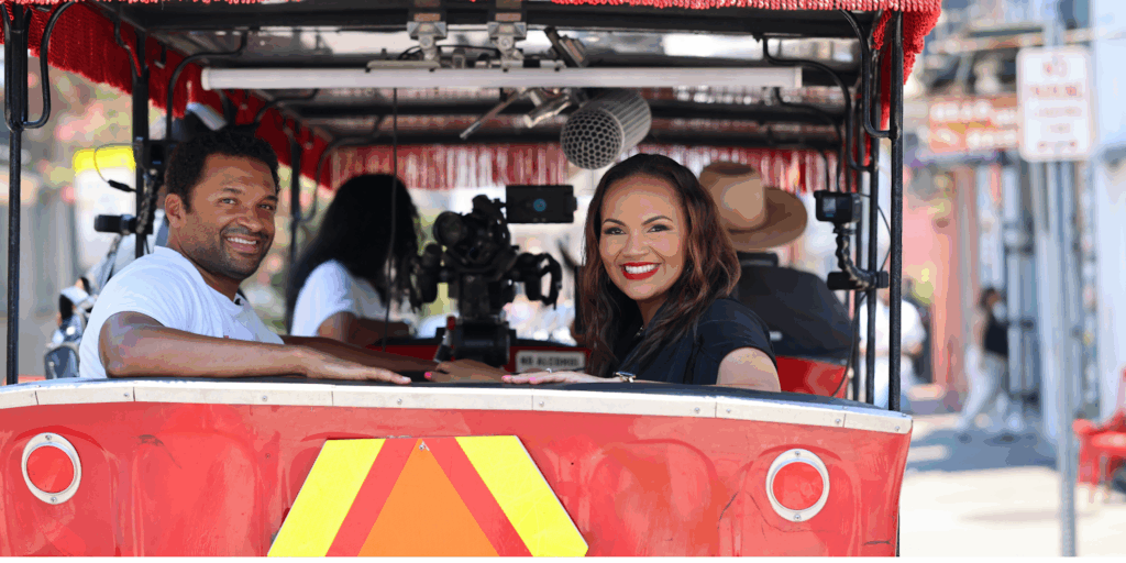 Del Smith, CEO and co-founder, Acclinate and Tiffany Whitlow, co-founder and CDO, Acclinate, sitting side-by-side in a red, open-air vehicle, both smiling brightly at the camera.