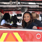 Del Smith, CEO and co-founder, Acclinate and Tiffany Whitlow, co-founder and CDO, Acclinate, sitting side-by-side in a red, open-air vehicle, both smiling brightly at the camera.