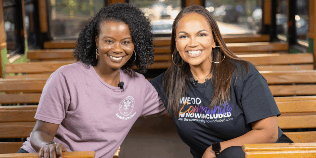 Michelle Brantley-Smith, founder of The Good Root Grove Co., and Tiffany Whitlow, Co-founder and CDO, Acclinate smiling together while sitting on a wooden trolley.