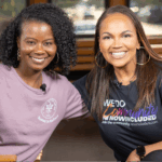 Michelle Brantley-Smith, founder of The Good Root Grove Co., and Tiffany Whitlow, Co-founder and CDO, Acclinate smiling together while sitting on a wooden trolley.