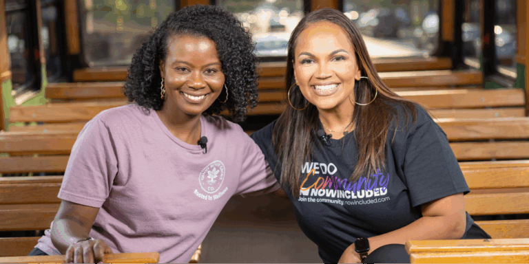 Michelle Brantley-Smith, founder of The Good Root Grove Co., and Tiffany Whitlow, Co-founder and CDO, Acclinate smiling together while sitting on a wooden trolley.