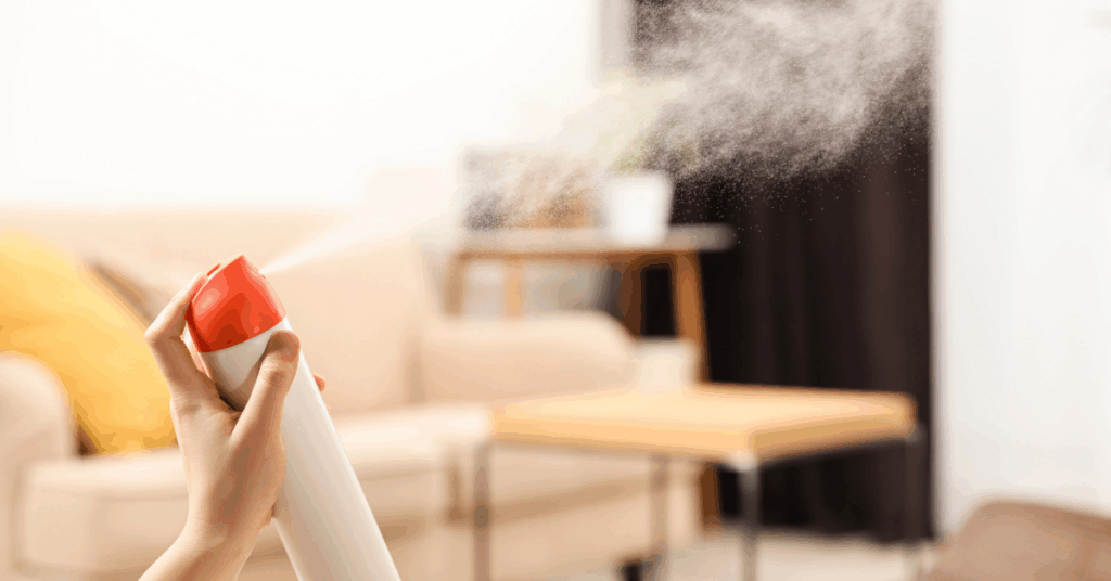 Close-up of a hand holding an air freshener can and spraying their living room