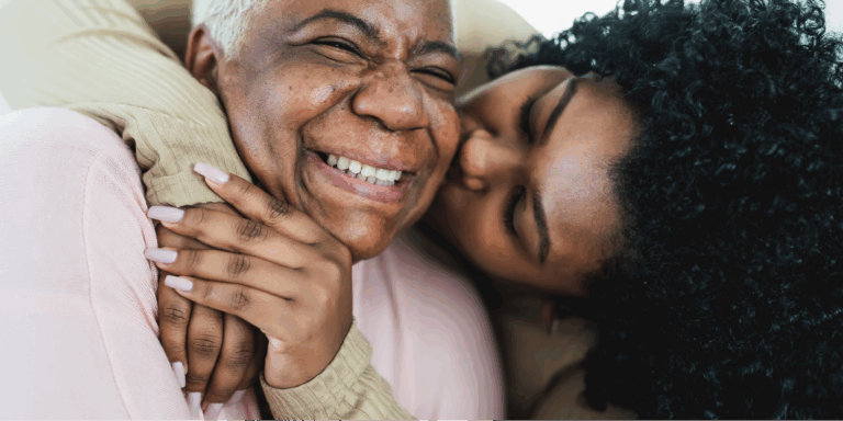 Radon and Lung Cancer: What’s the Connection? 1 Close-up image of an older Black woman with gray hair, likely living with breast cancer, and a younger Black woman with curly hair hugging, both smiling with eyes closed.
