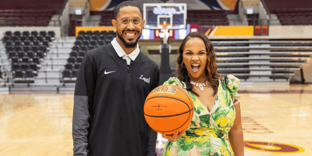 Jordan McCann, Assistant Women’s Basketball Coach and Recruiting Director at Loyola University and Tiffany Whitlow, co-founder and CDO, Acclinate, both smiling and looking excited, holding a basketball in a stadium on a basketball court.