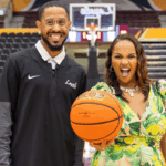 Jordan McCann, Assistant Women’s Basketball Coach and Recruiting Director at Loyola University and Tiffany Whitlow, co-founder and CDO, Acclinate, both smiling and looking excited, holding a basketball in a stadium on a basketball court.