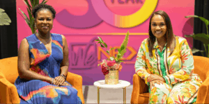 Tawa Mitchell, Senior Program Officer at the MacArthur Foundation and Tiffany Whitlow, Co-founder and CDO, Acclinate, smiling on stage at the Black Women&rsquo;s Expo in Chicago.