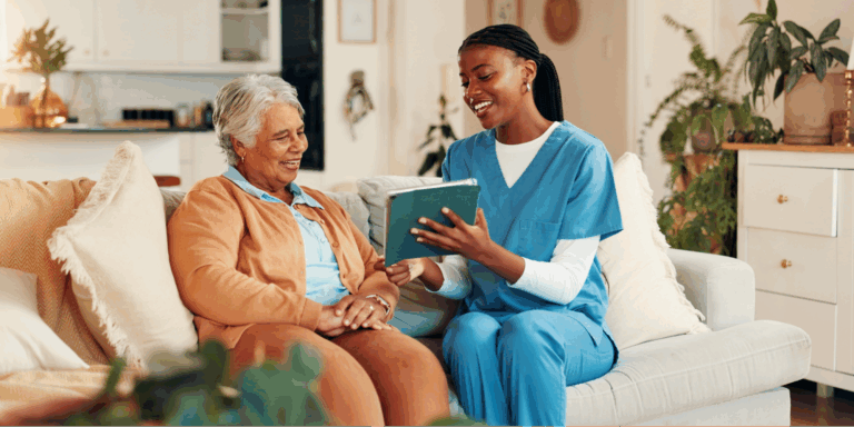 A young Black health aide sitting on a couch with a Black elderly woman to navigate caregiver rights, FMLA leave, and Social Security Disability (SSDI) benefits.