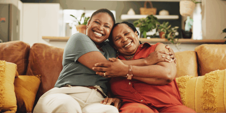 5 Black Celebrities With Lung Cancer 1 A close-up of two Black women smiling and embracing at home, highlighting the importance of shared health awareness to lower your breast cancer risk.