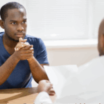 A Black man reviewing medical documents about GFR score and kidney health function with a Black male physician.